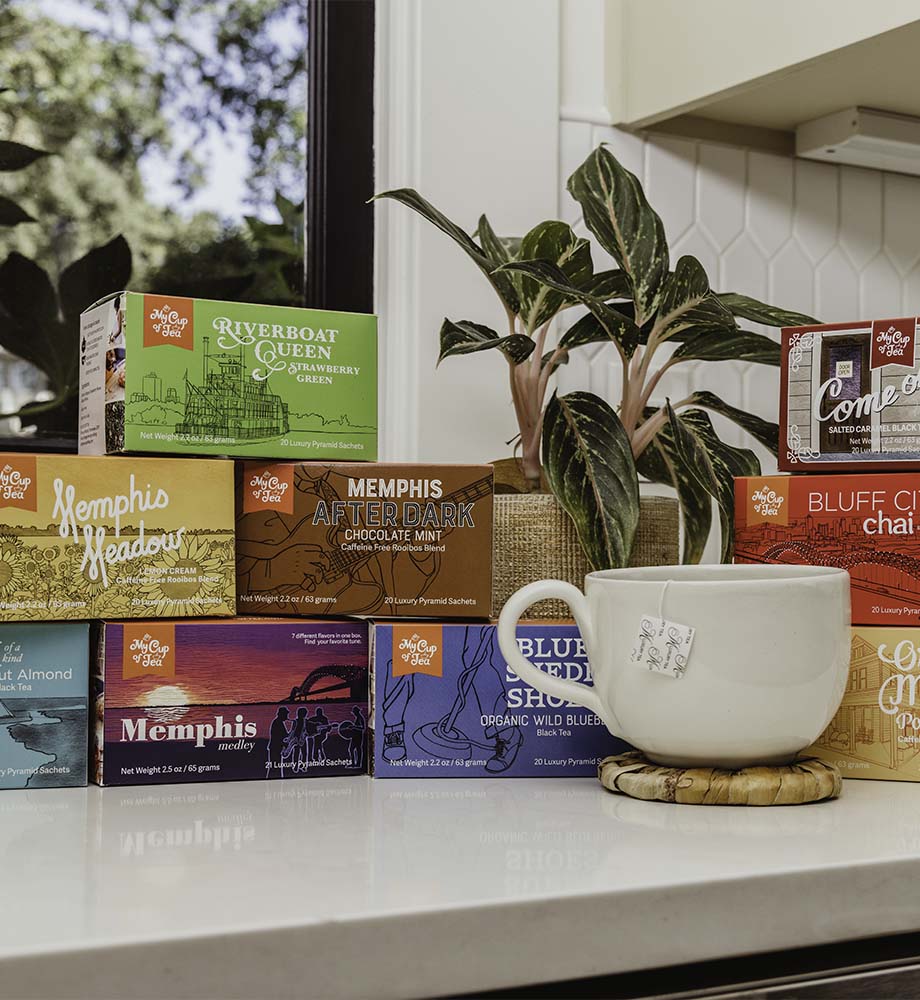 Various tea boxes from My Cup of Tea with a soup mug and banana leaf coaster on white countertop