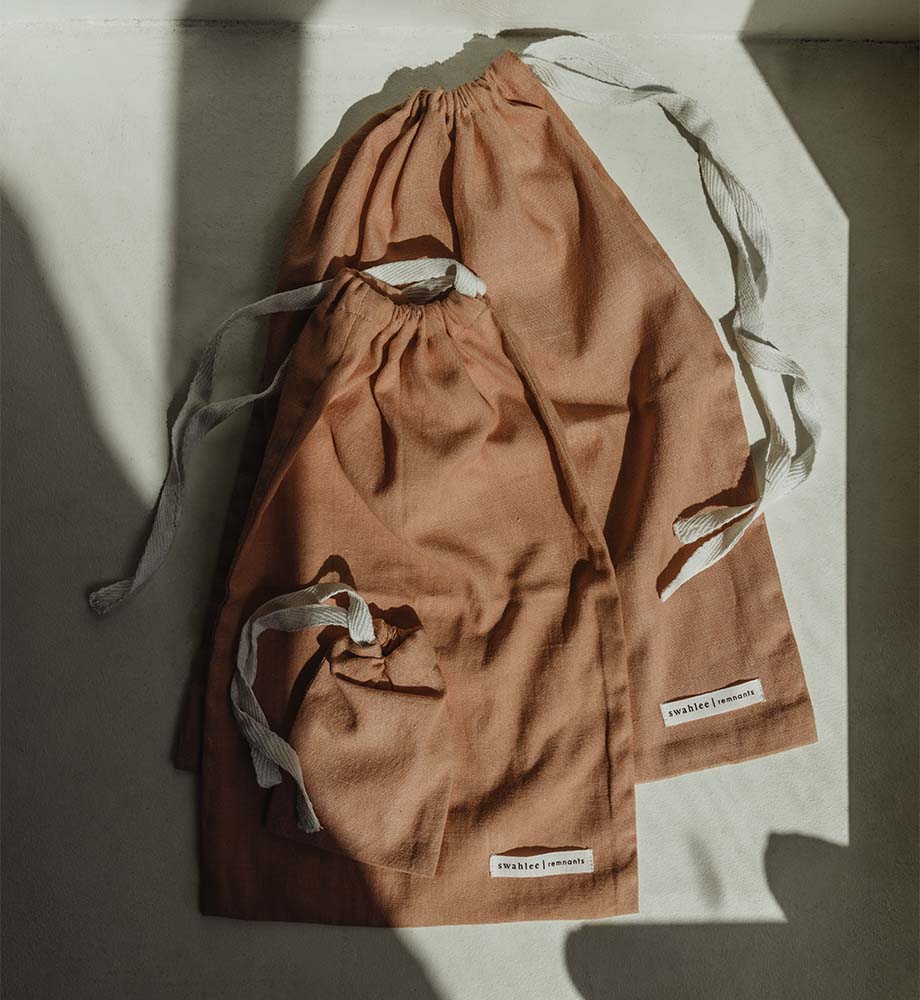 Three coral bags lay in the sun with shadows coming across it